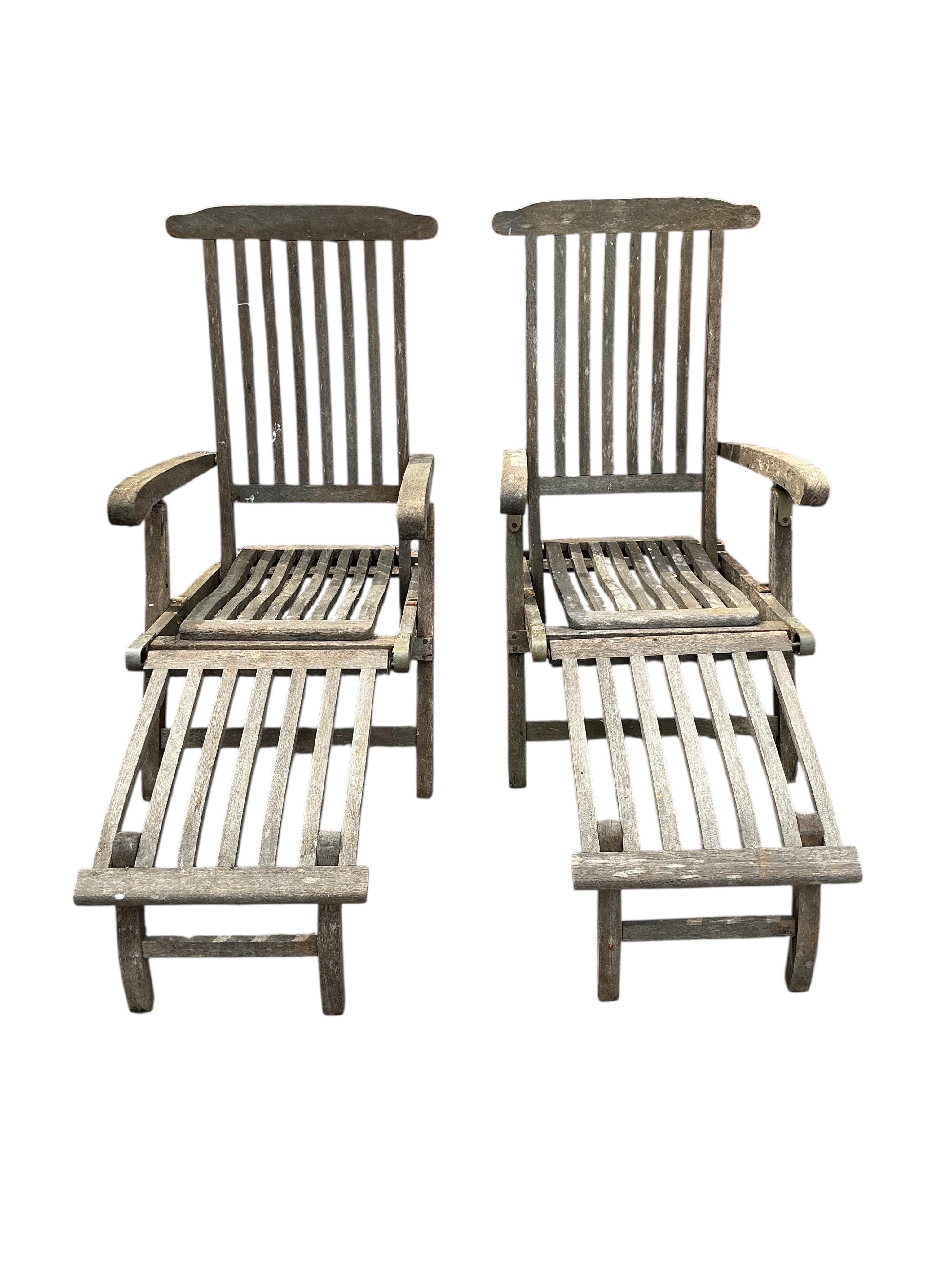 A pair of weathered teak garden steamer chairs